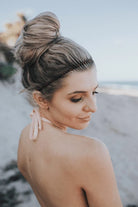 Woman on the beach wearing the Teleties Spiral Hair Coil Headband in tortoise with a top bun