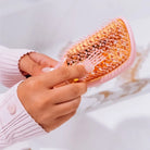 Hands holding the Teleties Vented Brush in Bubblegum Pink, close-up of bristles