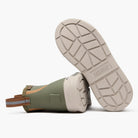 Bottom view of olive XTRATUF kids' deck boots showing the light-colored BioLite outsole and chevron tread.